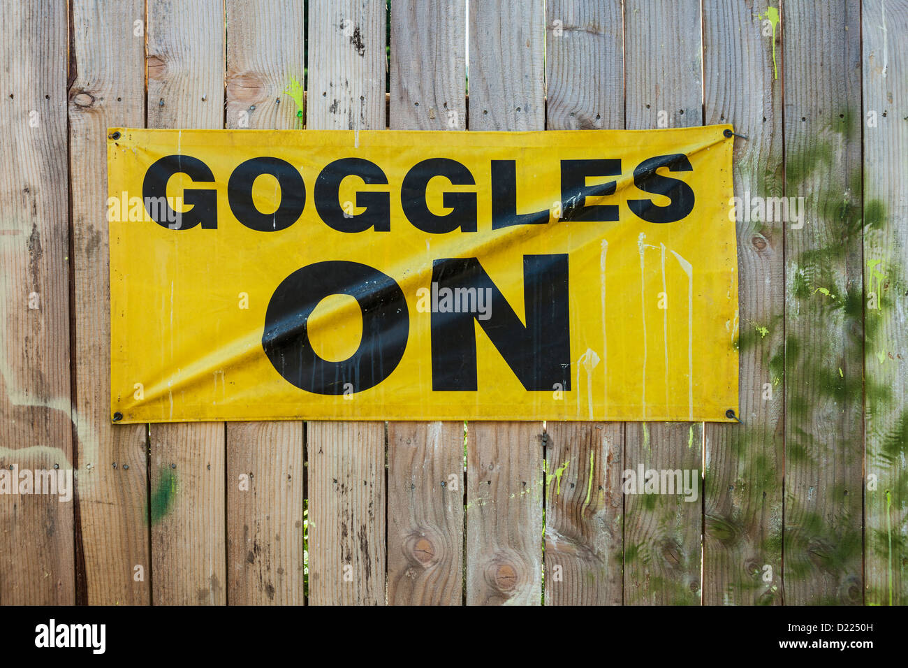 Goggles on sign on wooden fence at paintball field, Oregon Stock Photo