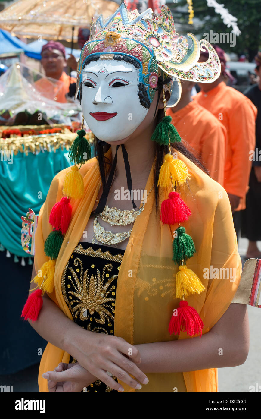 A woman wearing a traditional painted mask takes part in a Harvest Festival parade in the village of Tumpang, Java, Indonesia Stock Photo