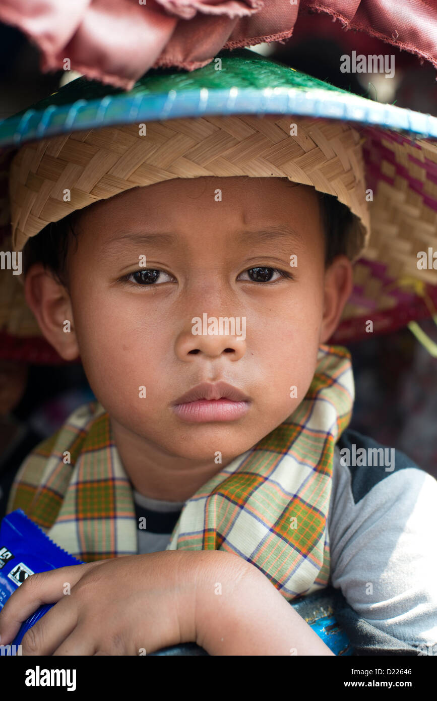 A boy wearing a traditional conical hat looks at the camera at a ...