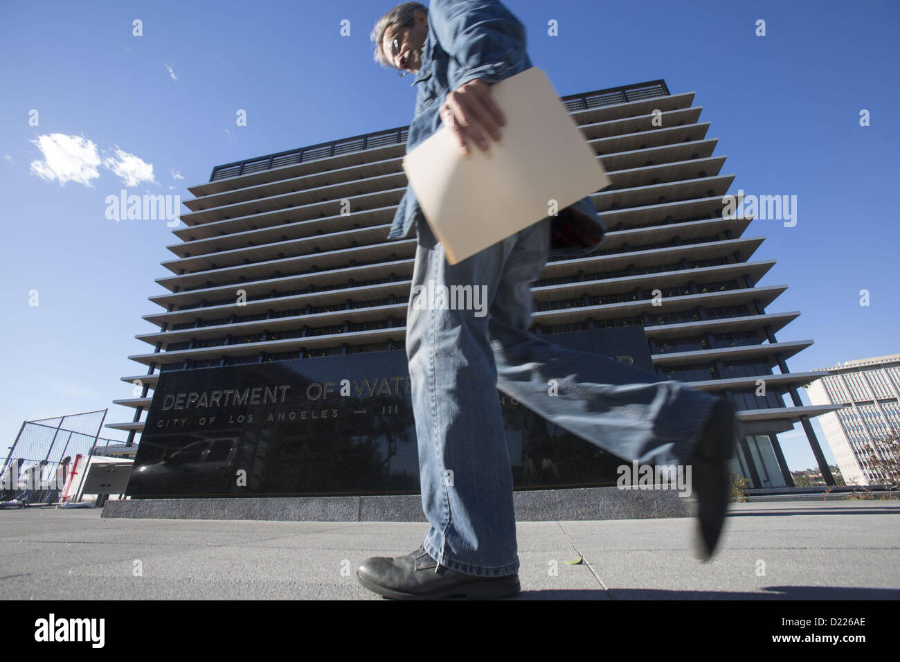 Jan. 11, 2013 - Los Angeles, California (CA, United States - A man walks past the headquater of the Department of Water and Power in downtown Los Angeles, Friday, January 11, 2013. The Board of Water and Power Commissioners today unanimously approved a $530 million program to pay approved commercial, industrial and residential property owners for electricity generated from their solar panels. The approval to sign 20-year contracts with customers who install minimum 30 kilowatt-hour solar power systems will make Los Angeles the largest city in the nation to have a so-called Feed-in-Tariff progr Stock Photo