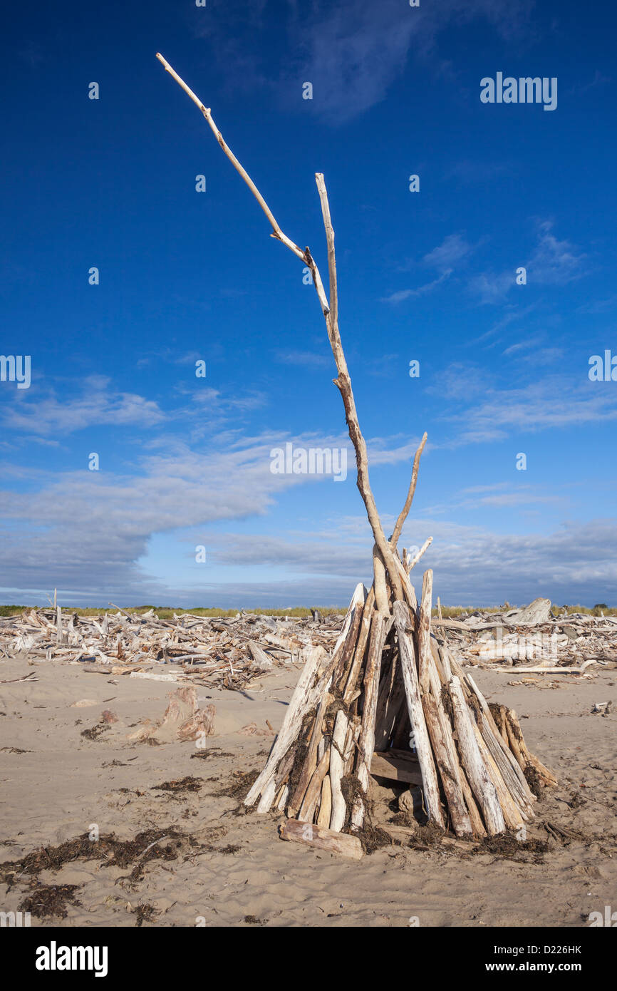 A teepee constructed of driftwood offers protection from the wind, Bandon, Oregon Stock Photo