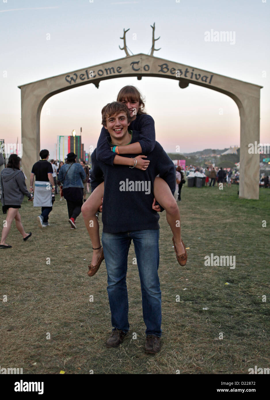 a girl gets a piggy back from friend at the welcome gate at BESTIVAL FESTIVAL, ISLE OF WHITE, SEPTEMBER 2012 Stock Photo