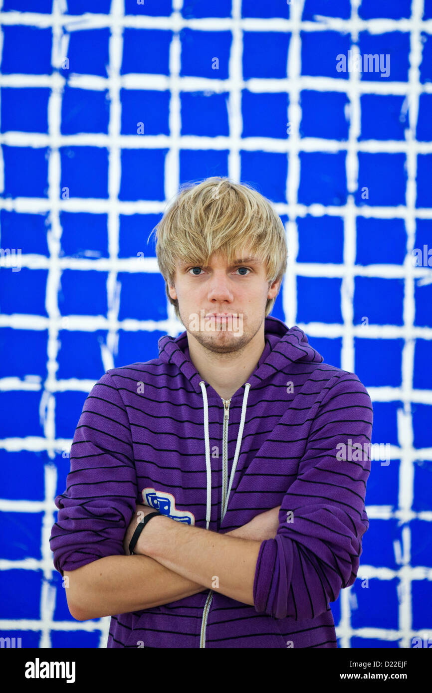 Man standing in front of blue wall Stock Photo - Alamy