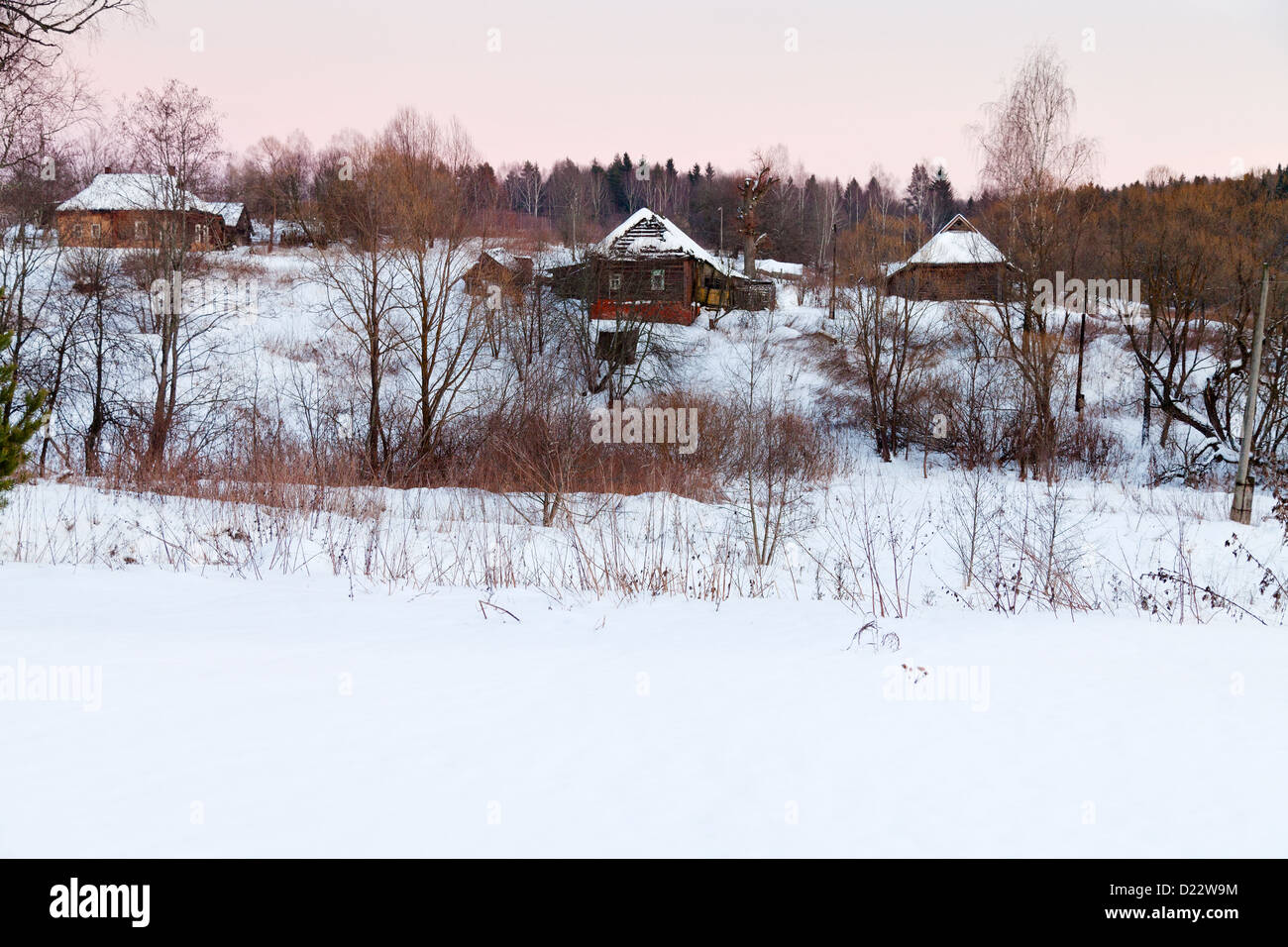 rural landscape with snowy wooden houses in country at pink winter ...