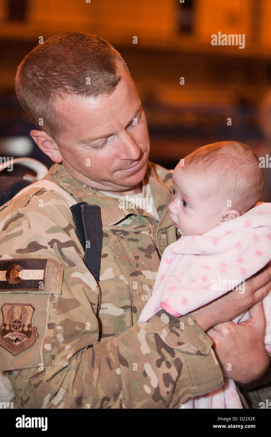 A member of the Colorado Air National guard holds his daughter for the first time after returning home at Buckley Air Force Base Colo., Jan 10, 2013. The 140th Wing, Colorado Air National Guard enjoyed a safe return home after completing a three-month mis Stock Photo
