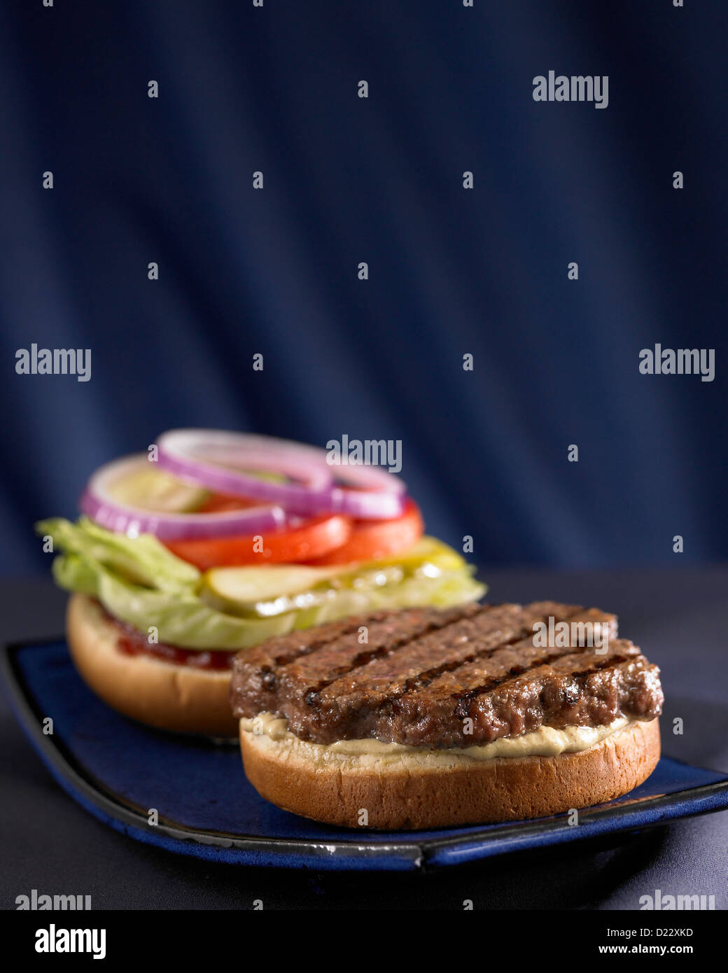 Open faced hamburger with lettuce pickle tomato and onion Stock Photo