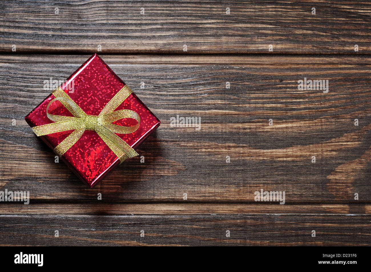 Red gif box with golden ribbon on wooden background Stock Photo