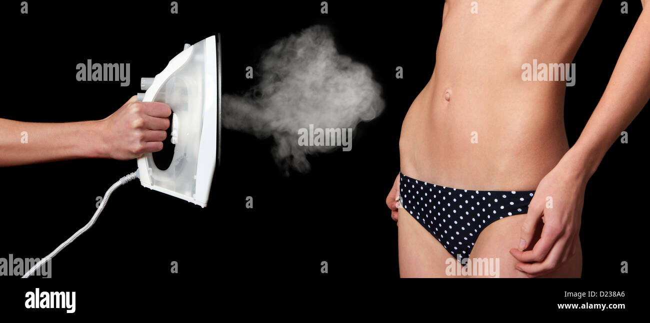 Steam iron being used to flatten a woman's stomach Stock Photo