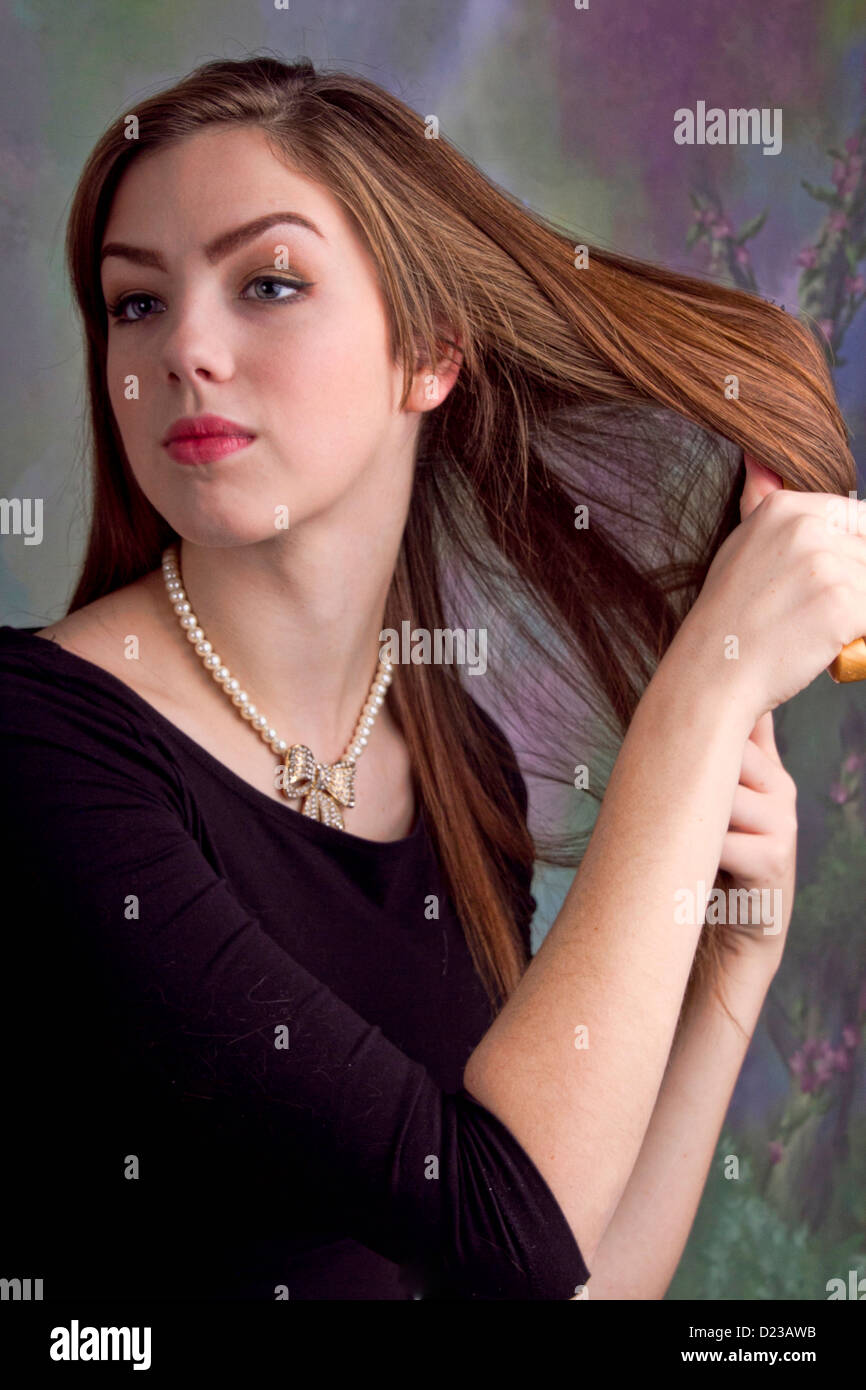 An adult young woman brushing her long brown hair. Stock Photo