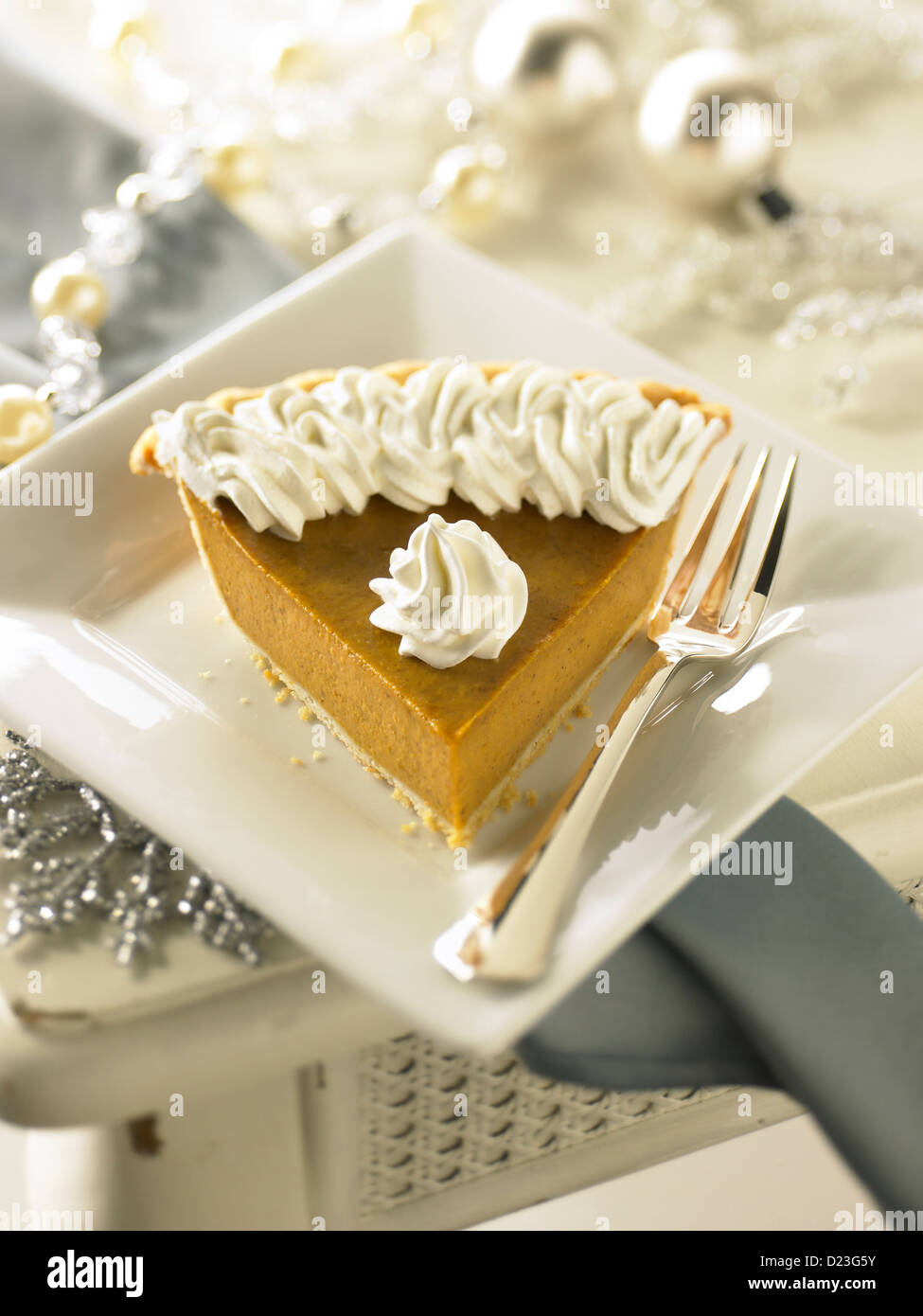 Pumpkin pie slice in a holiday setting Stock Photo