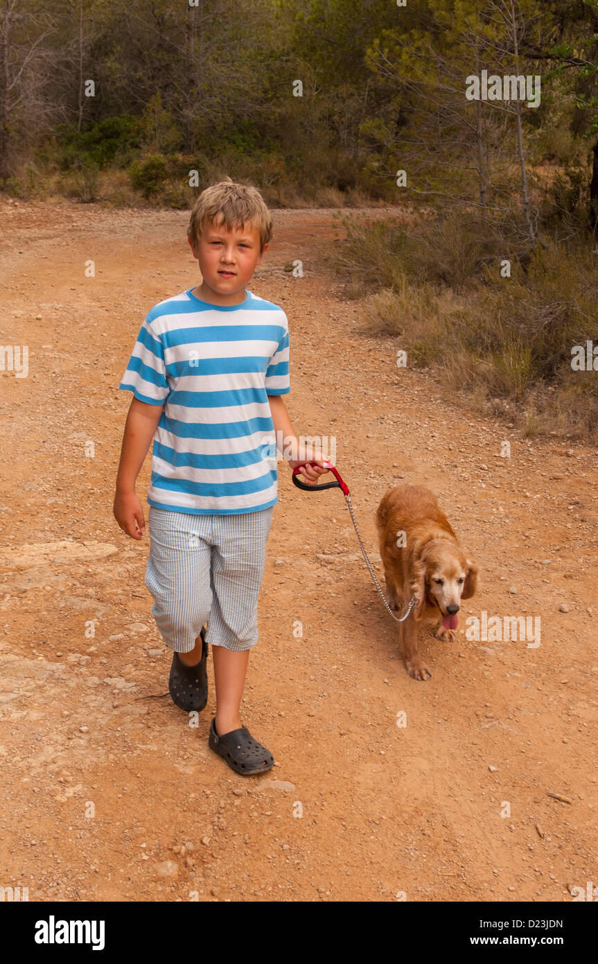 An 8 year old boy walking a cocker spaniel dog in Spain Stock Photo
