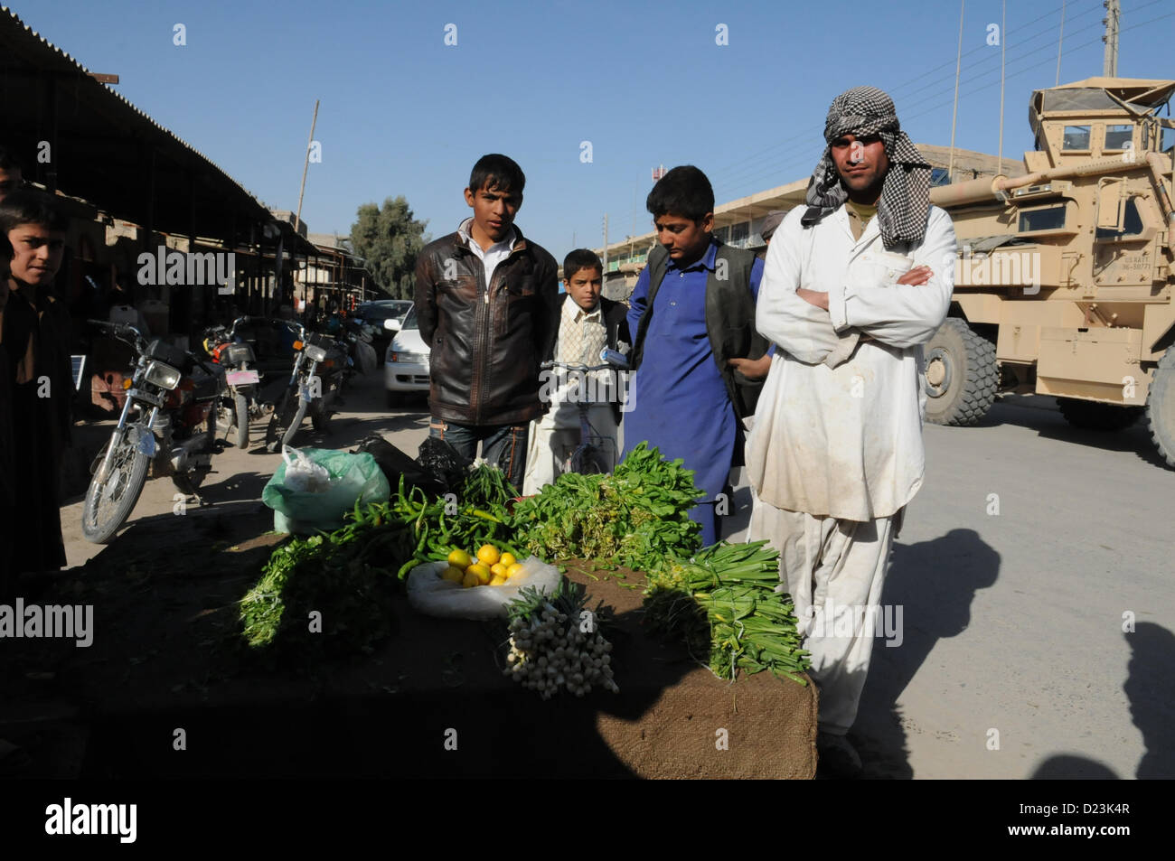 An Afghan produce seller, right, stands next to his vegetable cart in Farah City, Jan. 13.  PRT Farah visited a nearby bank to discuss small business development and growth initiatives in Farah.  PRT Farah's mission is to train, advise, and assist Afghan government leaders at the municipal, district, and provincial levels in Farah province Afghanistan.  Their civil military team is comprised of members of the U.S. Navy, U.S. Army, the U.S. Department of State and the U.S. Agency for International Development (USAID).  (U.S. Navy photo by Lt. j.g. Matthew Stroup/released) Stock Photo