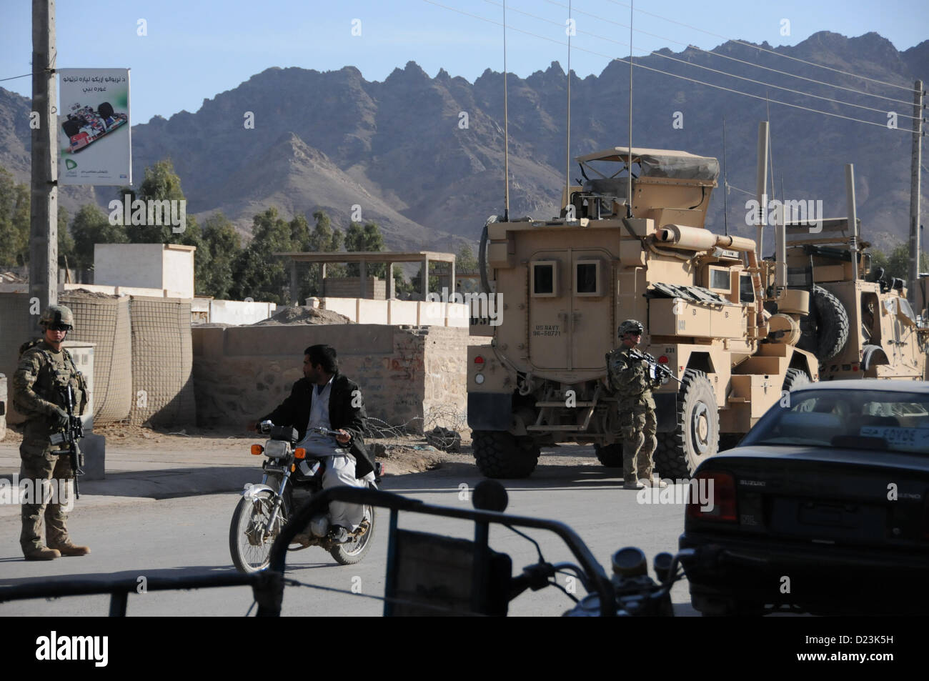 U.S. Army Spc. Matthew Gragg, left, and Pfc. Scott Yeates, right, security force team members for Provincial Reconstruction Team (PRT) Farah, pull security outside a bank in Farah City, Jan. 13.  PRT Farah visited bankers in Farah City to discuss small business development and growth initiatives in Farah.  PRT Farah's mission is to train, advise, and assist Afghan government leaders at the municipal, district, and provincial levels in Farah province Afghanistan.  Their civil military team is comprised of members of the U.S. Navy, U.S. Army, the U.S. Department of State and the U.S. Agency for Stock Photo