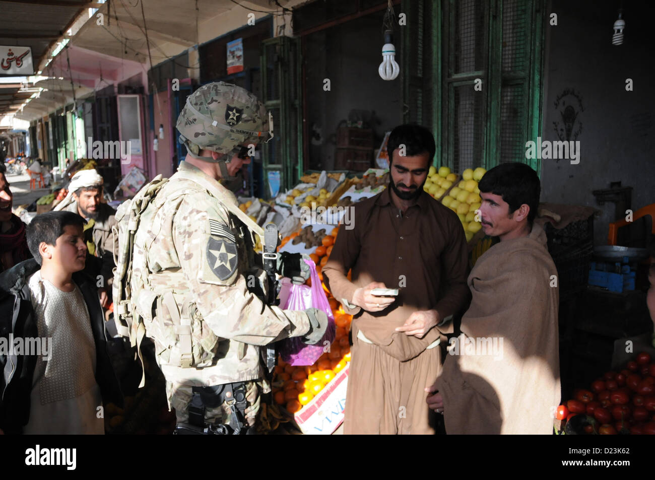 U.S. Army Pfc. Blake Shumway hands a local shopkeeper a handful of Afghani after purchasing a bag full of jujubes, a local specialty, at a Farah City market, Jan. 13.  PRT Farah visiteda nearby bank to discuss small business development and growth initiatives in Farah.  PRT Farah's mission is to train, advise, and assist Afghan government leaders at the municipal, district, and provincial levels in Farah province Afghanistan.  Their civil military team is comprised of members of the U.S. Navy, U.S. Army, the U.S. Department of State and the U.S. Agency for International Development (USAID).  ( Stock Photo