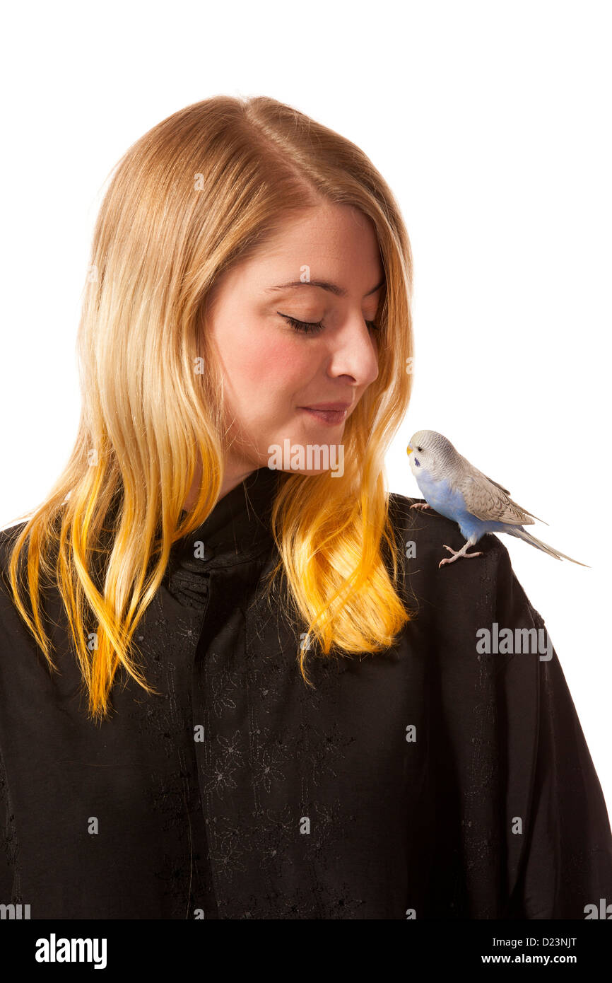 Friendly parakeet sitting on a womans shoulder. She is looking down on the bird. Stock Photo