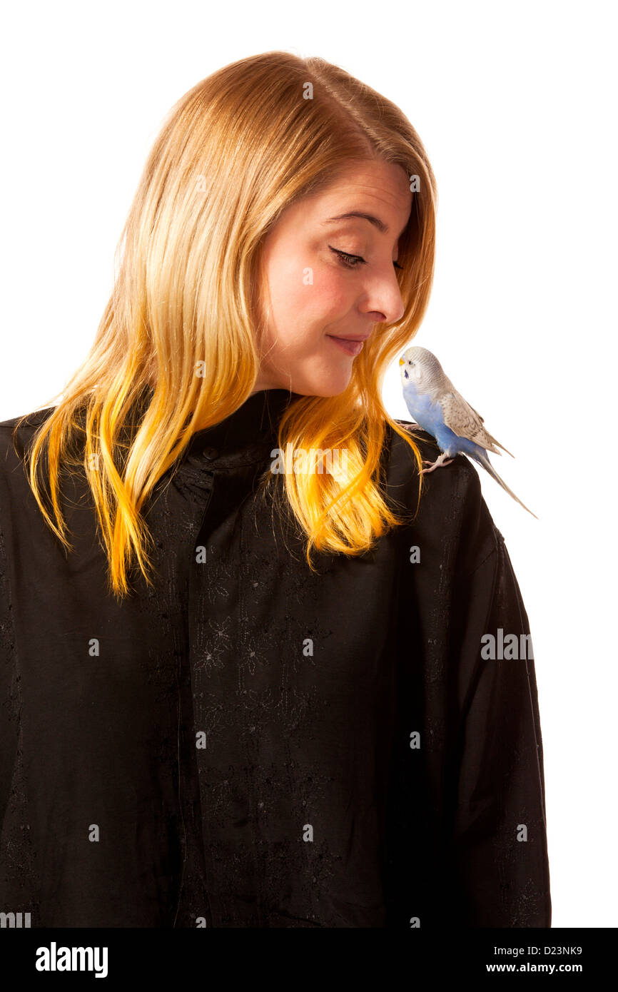 Friendly parakeet sitting on a womans shoulder. She is looking down on the bird. Stock Photo
