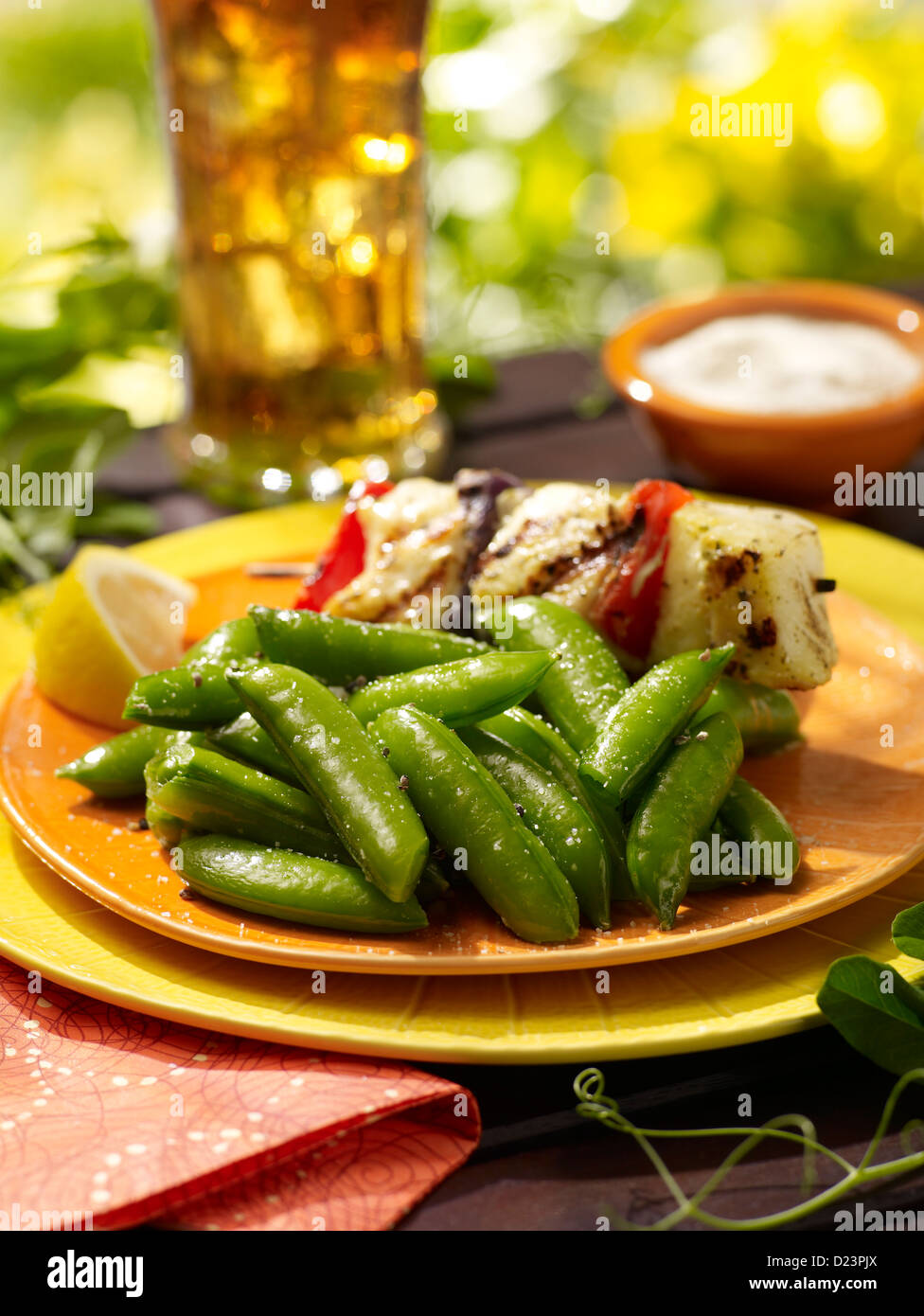 Sugar snap peas served with tofu and an ice tea in an outdoor summer setting Stock Photo