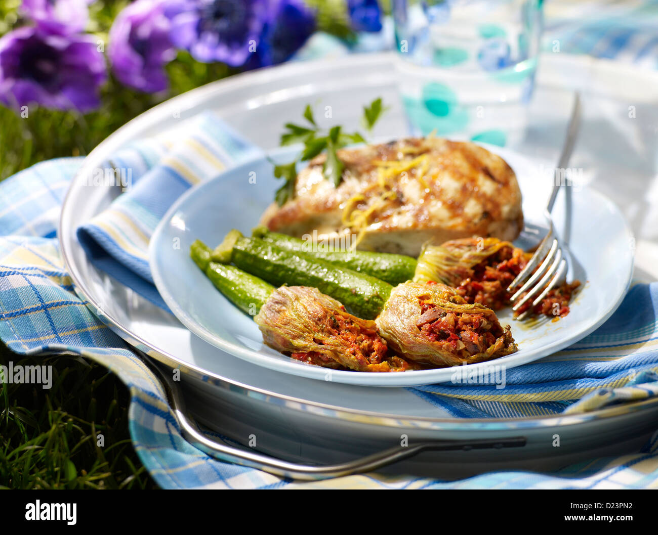 Stuffed squash blossoms with grilled chicken and zucchini in an outdoor picnic setting Stock Photo