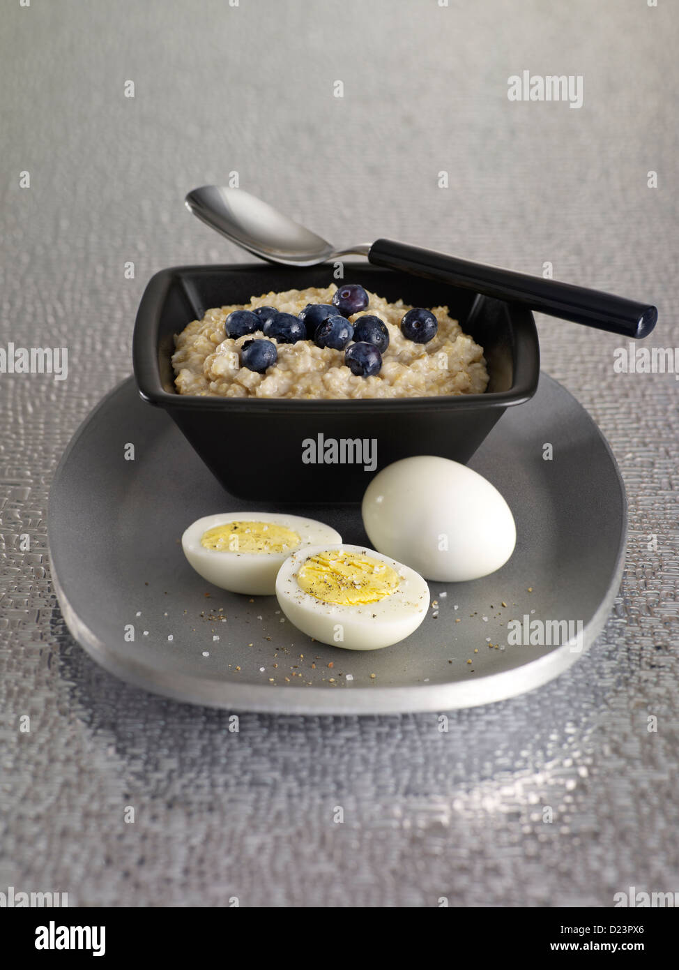 Oatmeal topped with blueberries and served with hard boiled eggs Stock Photo