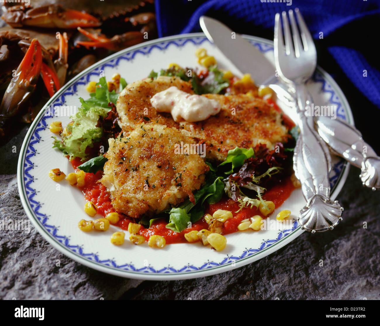 Crab cakes on a bed of lettuce topped with sauce Stock Photo