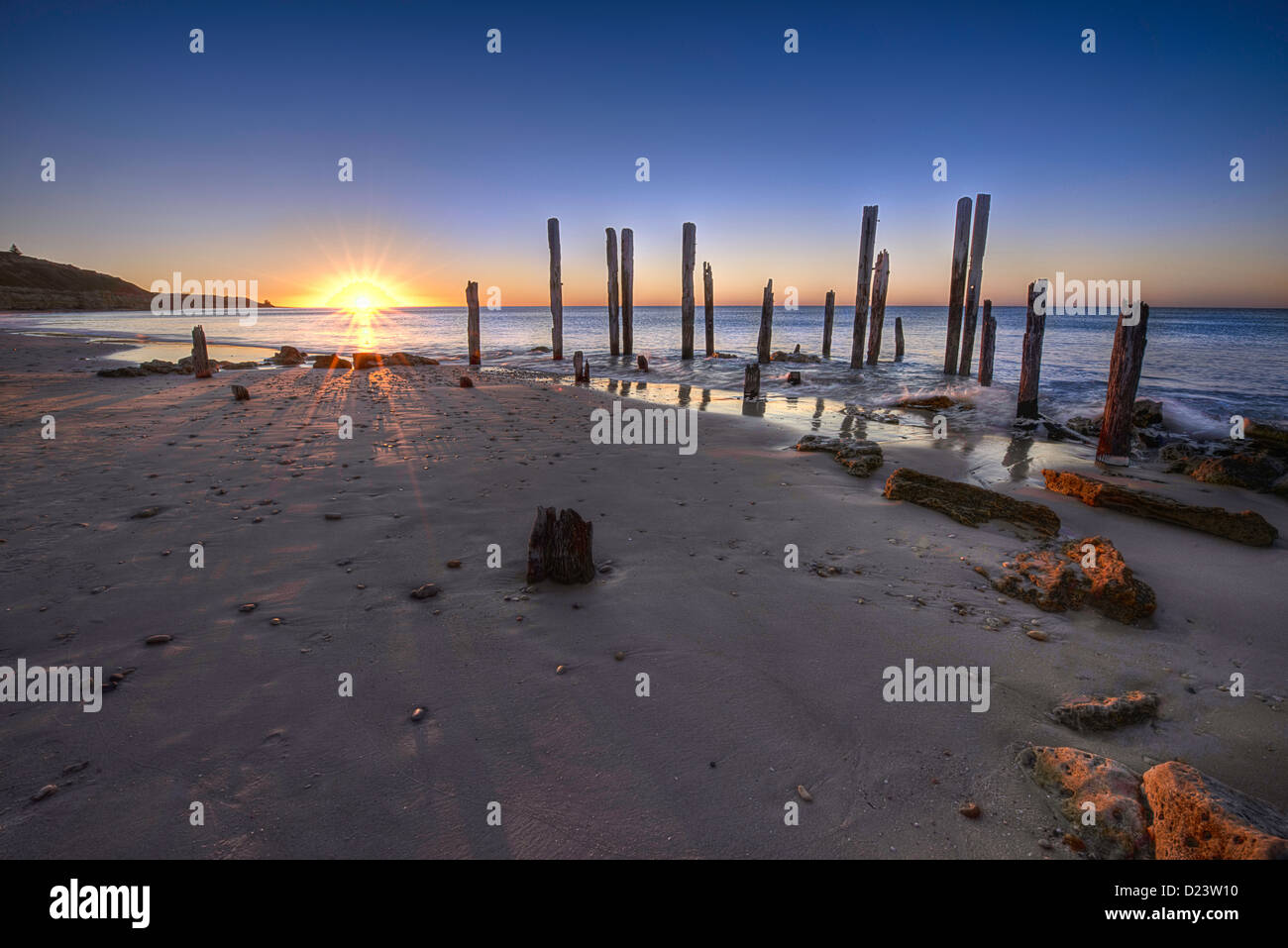 A spectacular sunset over the sea behind the remains of an old settlers' pier on Port Willunga beach. Stock Photo