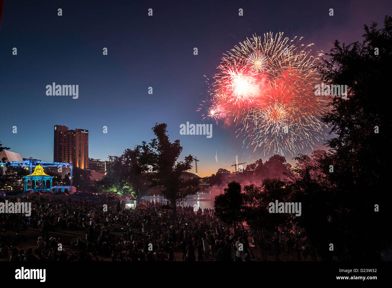 Revellers watch fireworks light up the sky at dusk in the city Stock Photo