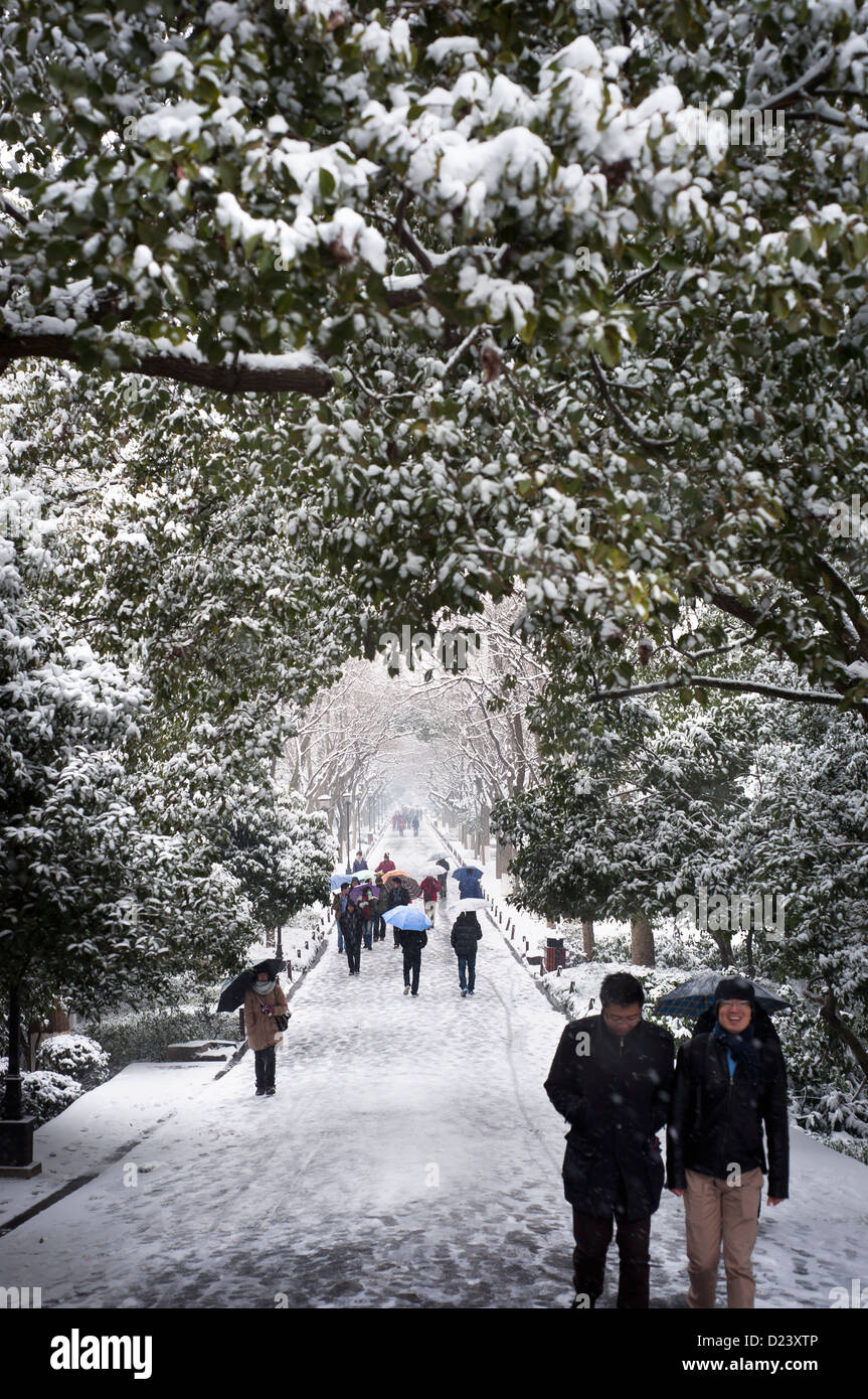 Tourists walk along Su Causeway, West Lake, during a snowy day in Hangzhou Stock Photo