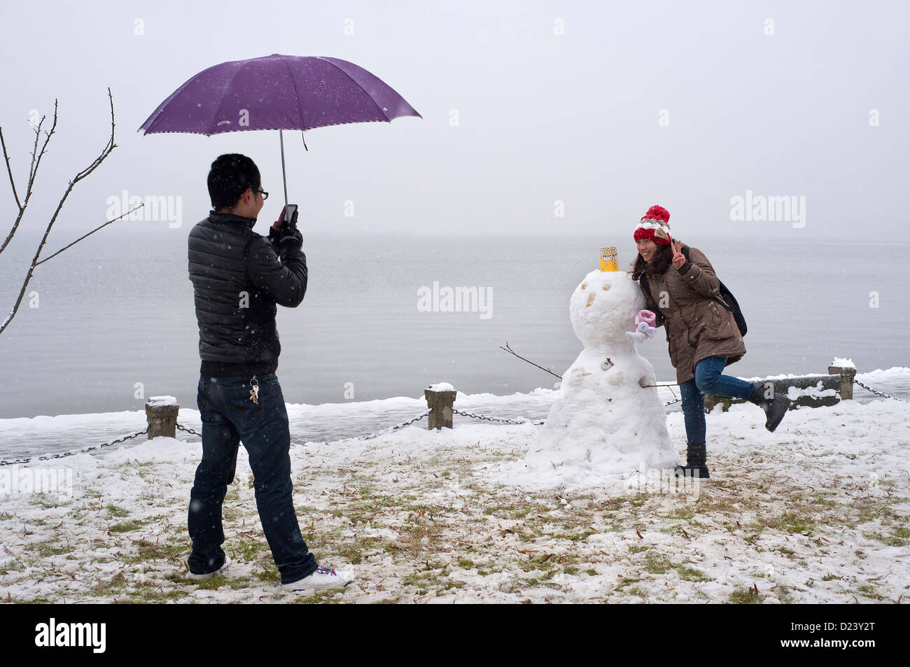 Young Chinese couple pose next to a snowman during winter at West Lake, Hangzhou, China Stock Photo