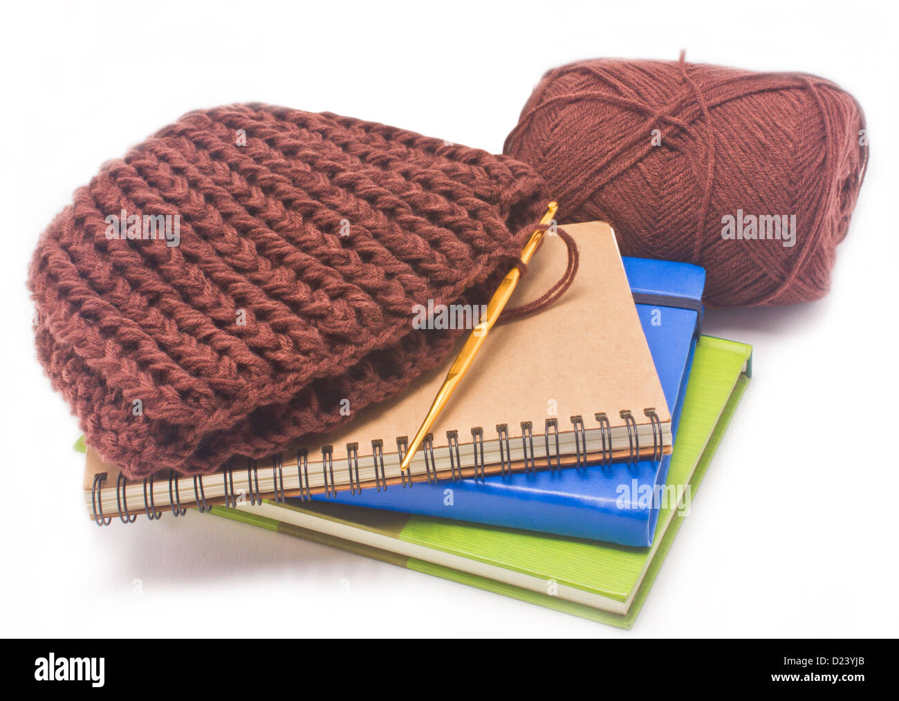 Brown crochet hat with golden hook, yarns and books isolated on white background. Stock Photo
