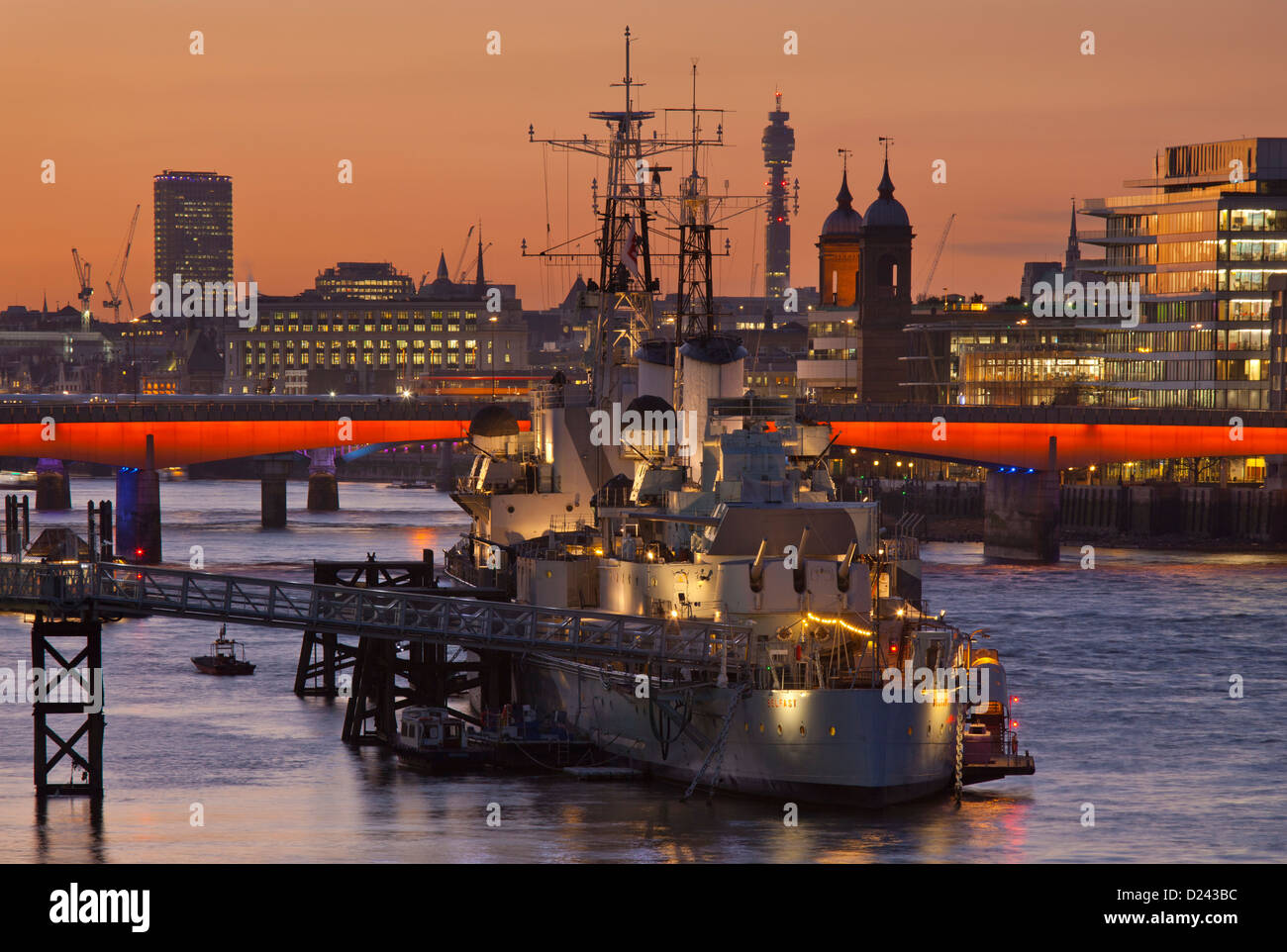 HMS Belfast moored on the Thames with London bridge skyline and post office tower in background at sunset, London, England Stock Photo