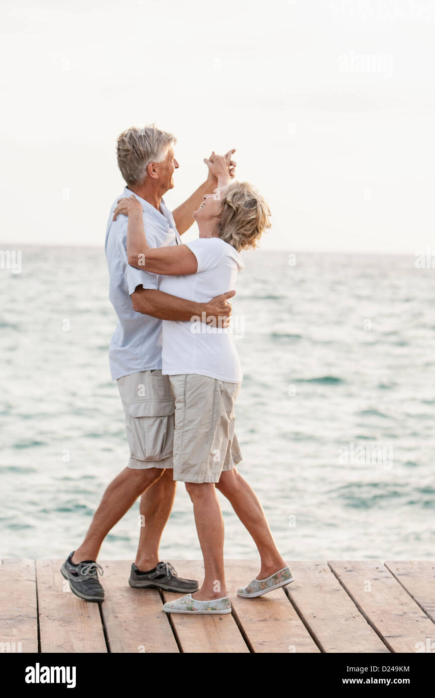 Spain, Senior couple dancing on jetty at the sea Stock Photo