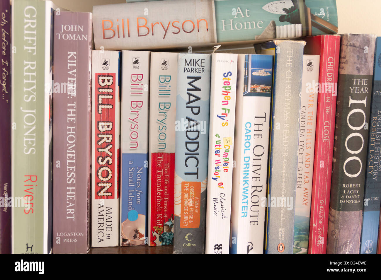 A shelf of mostly non-fiction paperback books including 'Notes from a Small Island' and ''The Olive Route'. Stock Photo