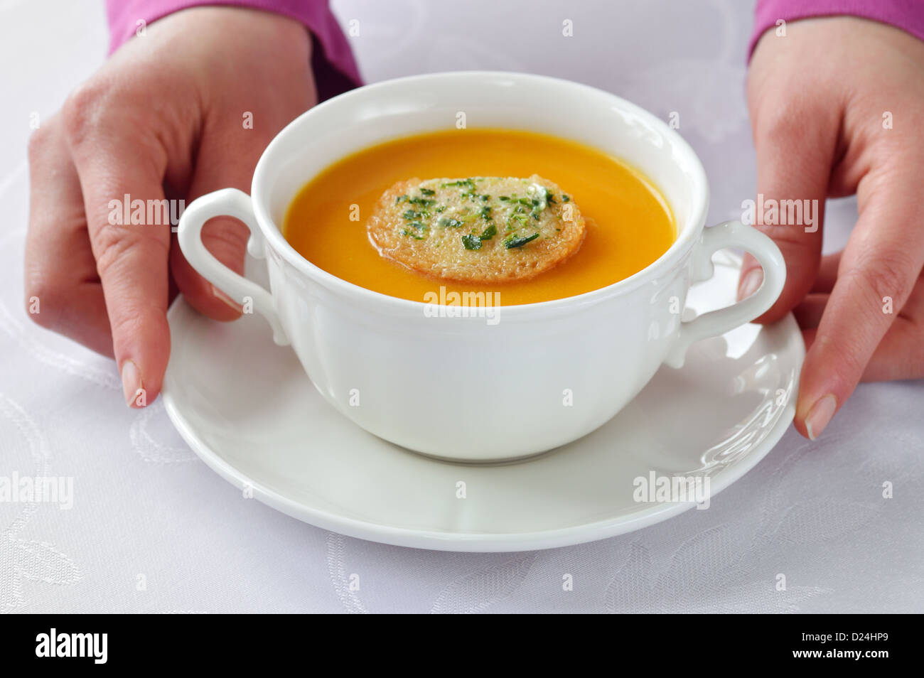 Serving homemade roasted-pumpkin soup in white bowl on white tablecloth. Stock Photo