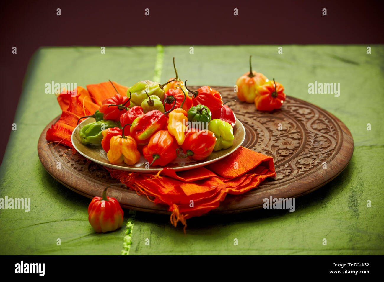 A plate of Scotch bonnet peppers on a carved wooden board Stock Photo