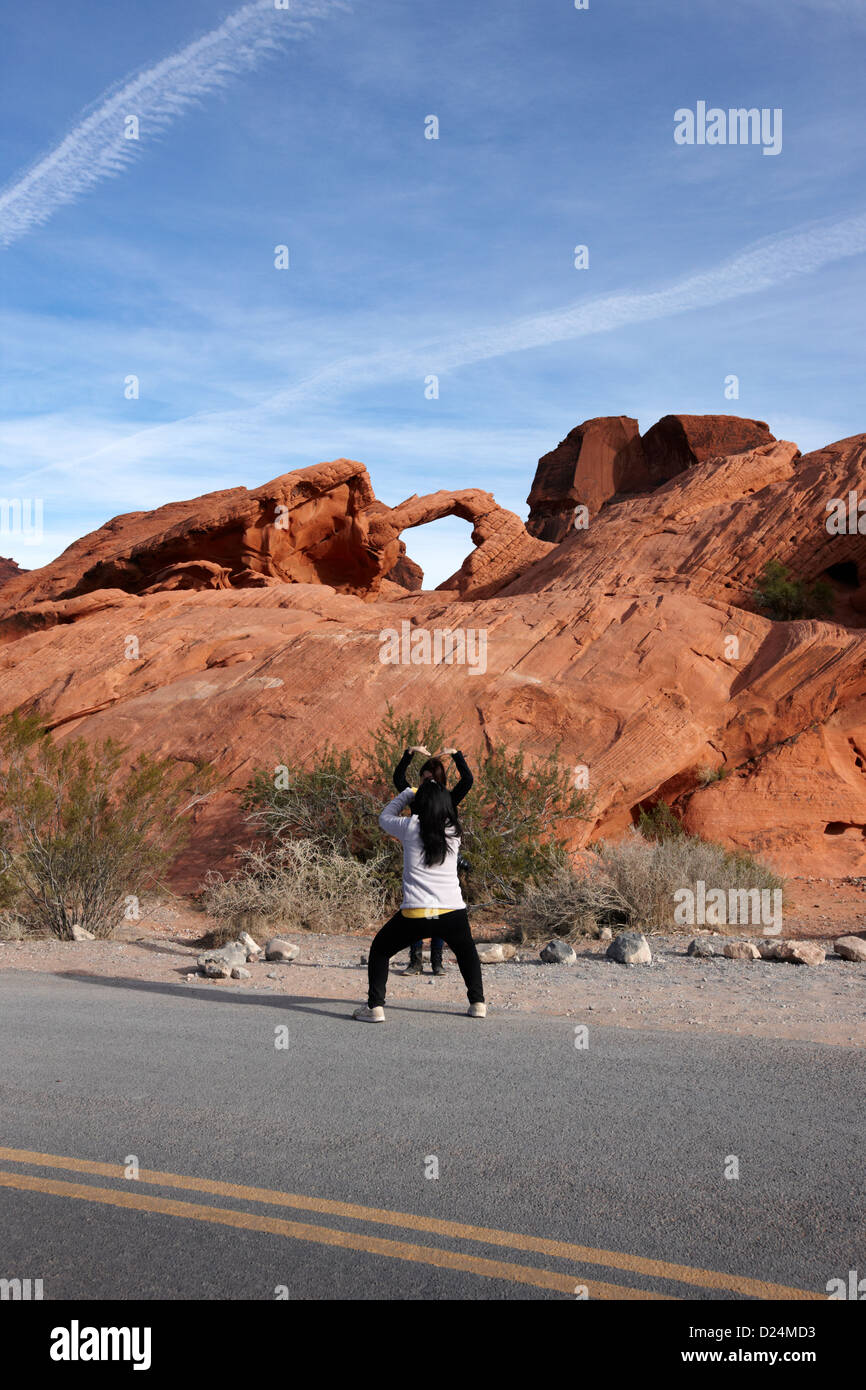 two female asian tourists pose and take photos in front of arch rock in the valley of fire state park nevada usa Stock Photo