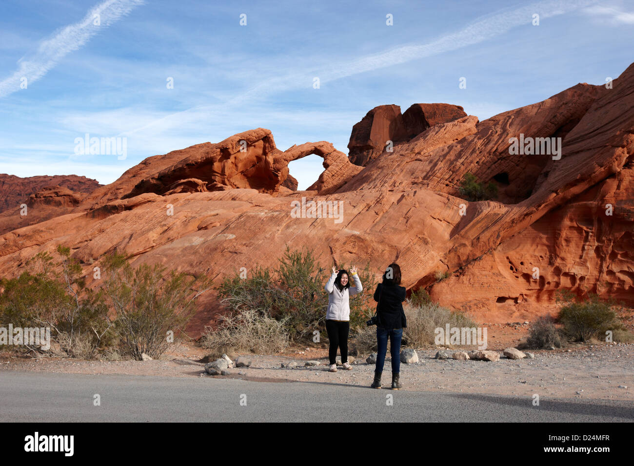 two female asian tourists pose and take photos in front of arch rock in the valley of fire state park nevada usa Stock Photo