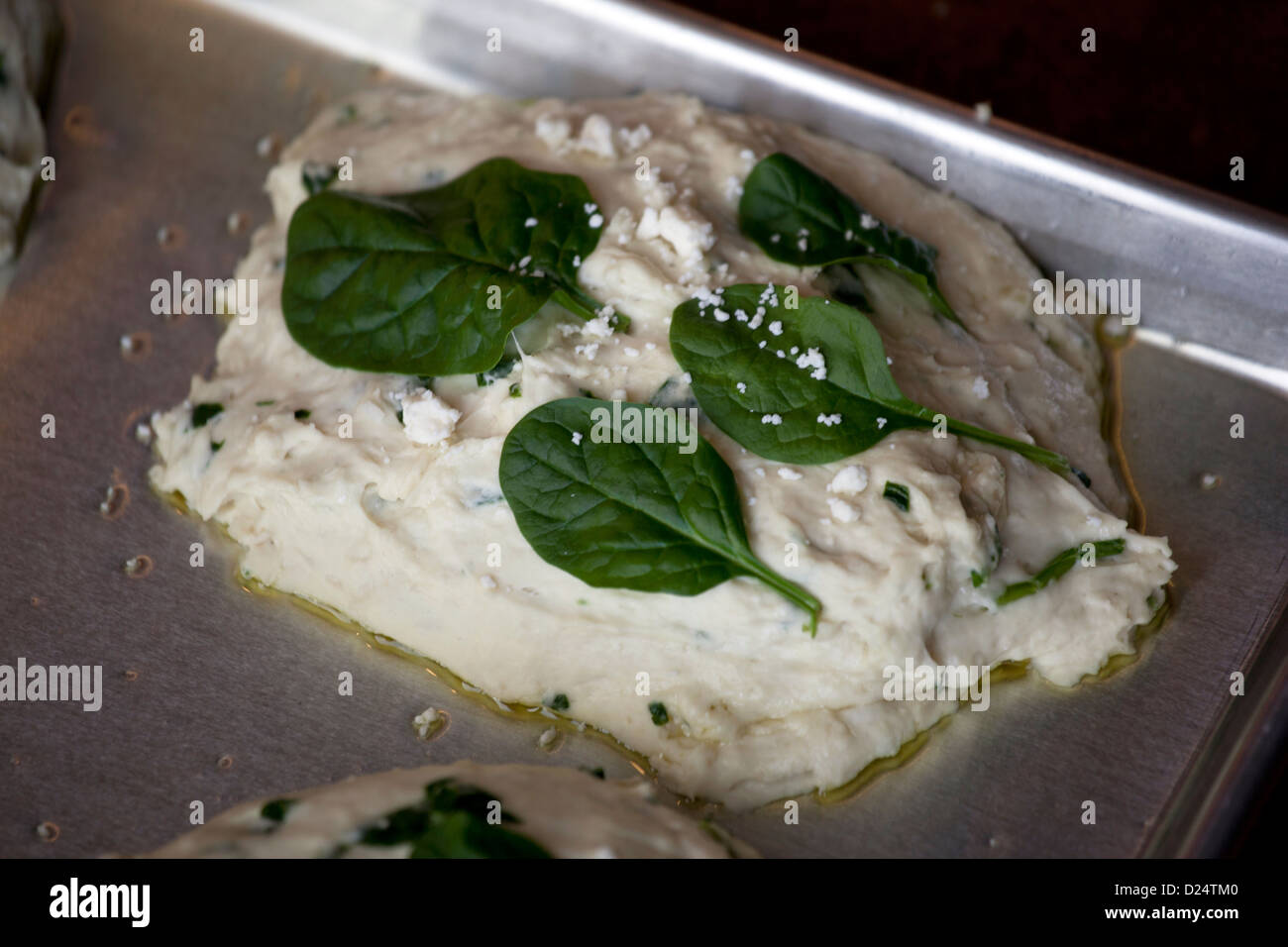 Fresh foccacia dough with spinach and feta cheese and olive oil on a cookie sheet Stock Photo