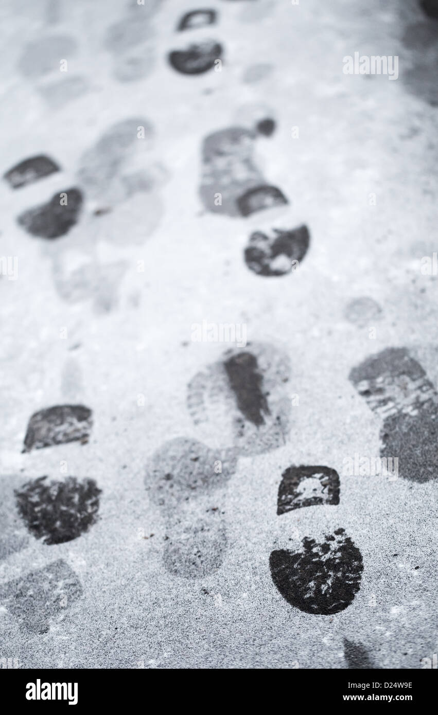 Footsteps in wet snow on asphalt urban road Stock Photo
