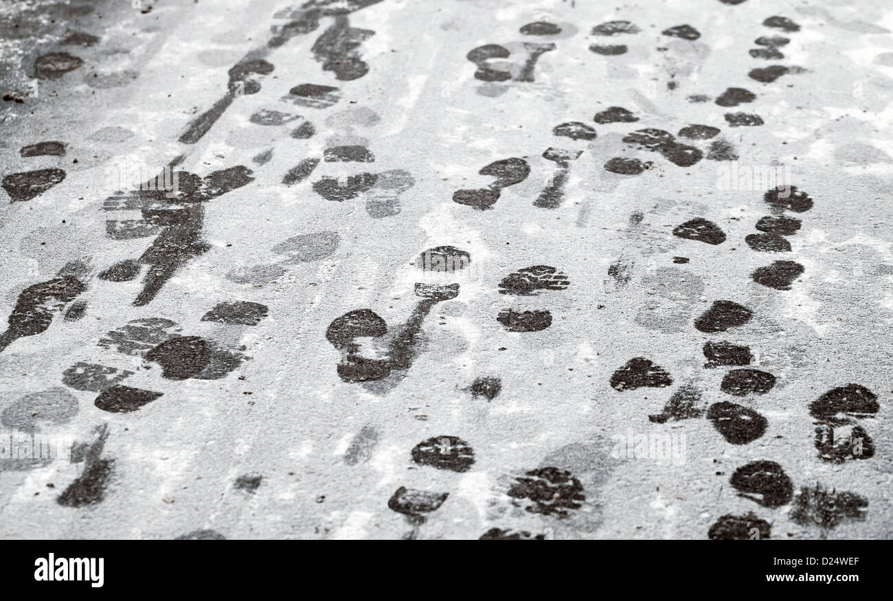 Footsteps in fresh wet snow on asphalt urban road Stock Photo