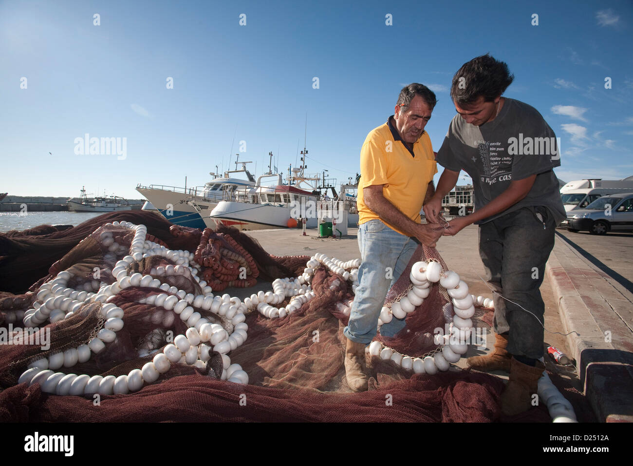 Sanlucar de Barrameda, Spain, two fishermen repair their nets on the harbor Stock Photo