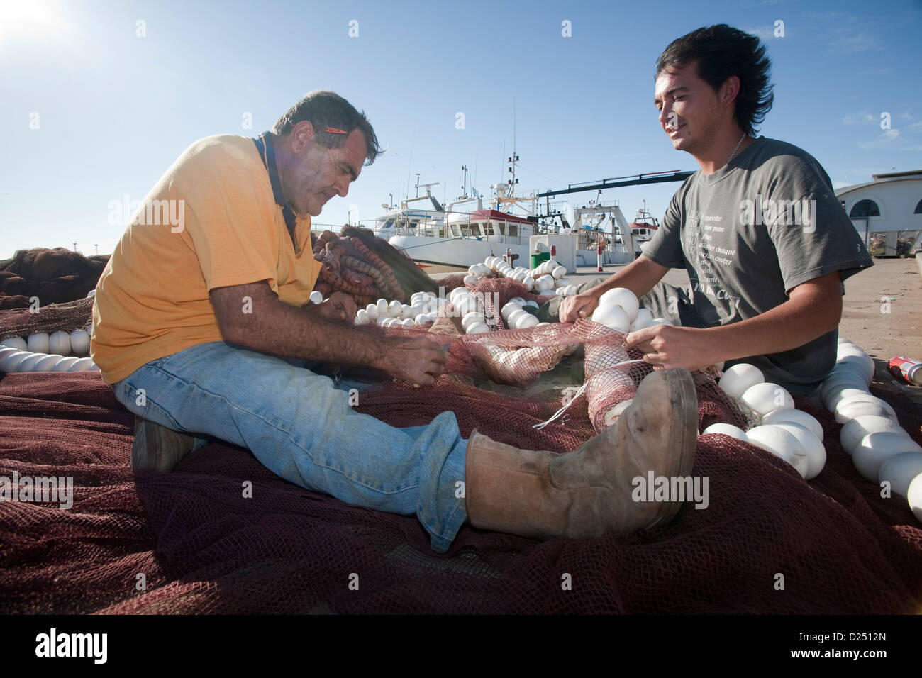 Sanlucar de Barrameda, Spain, two fishermen repair their nets on the harbor Stock Photo