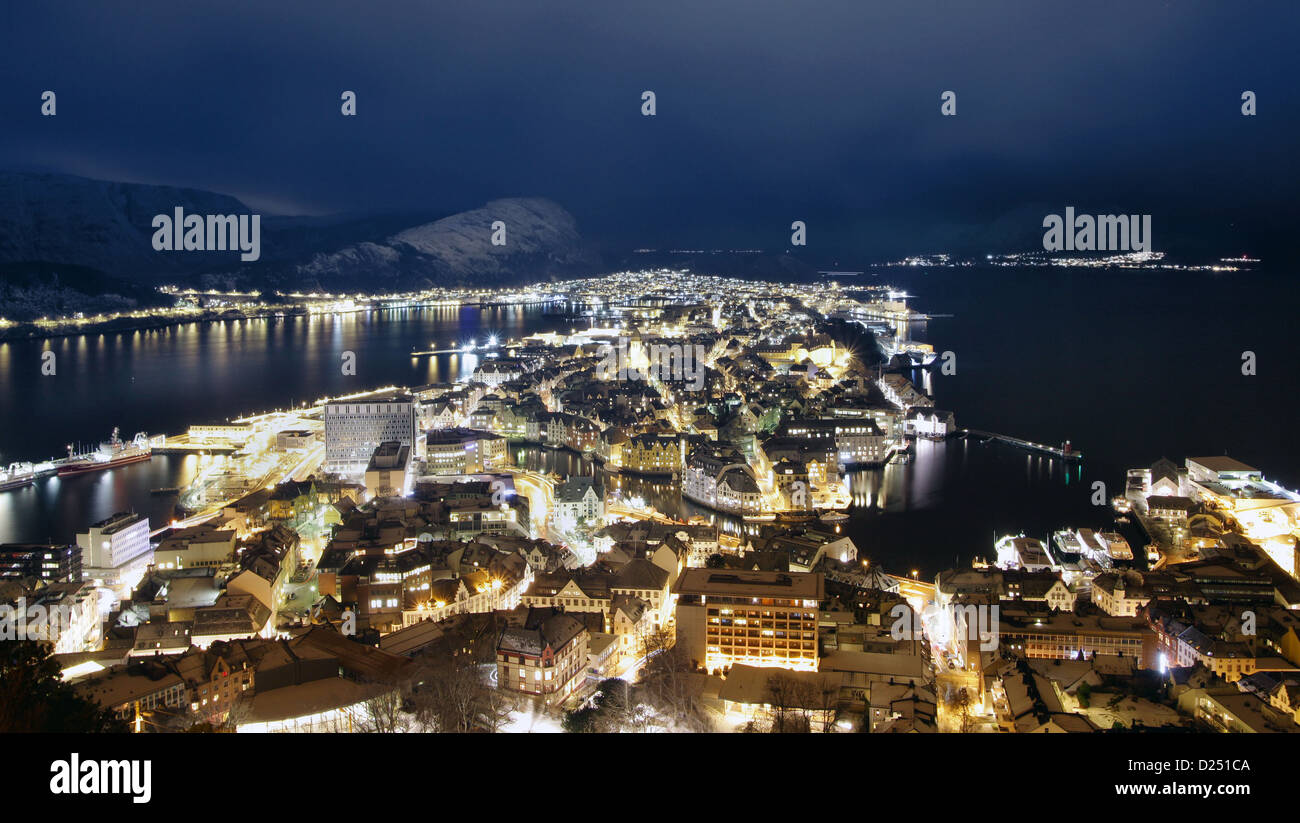 Panoramic aerial view of Alesund, Norway at night with snow capped mountains and traffic trails. Taken from mount Aksla. Stock Photo