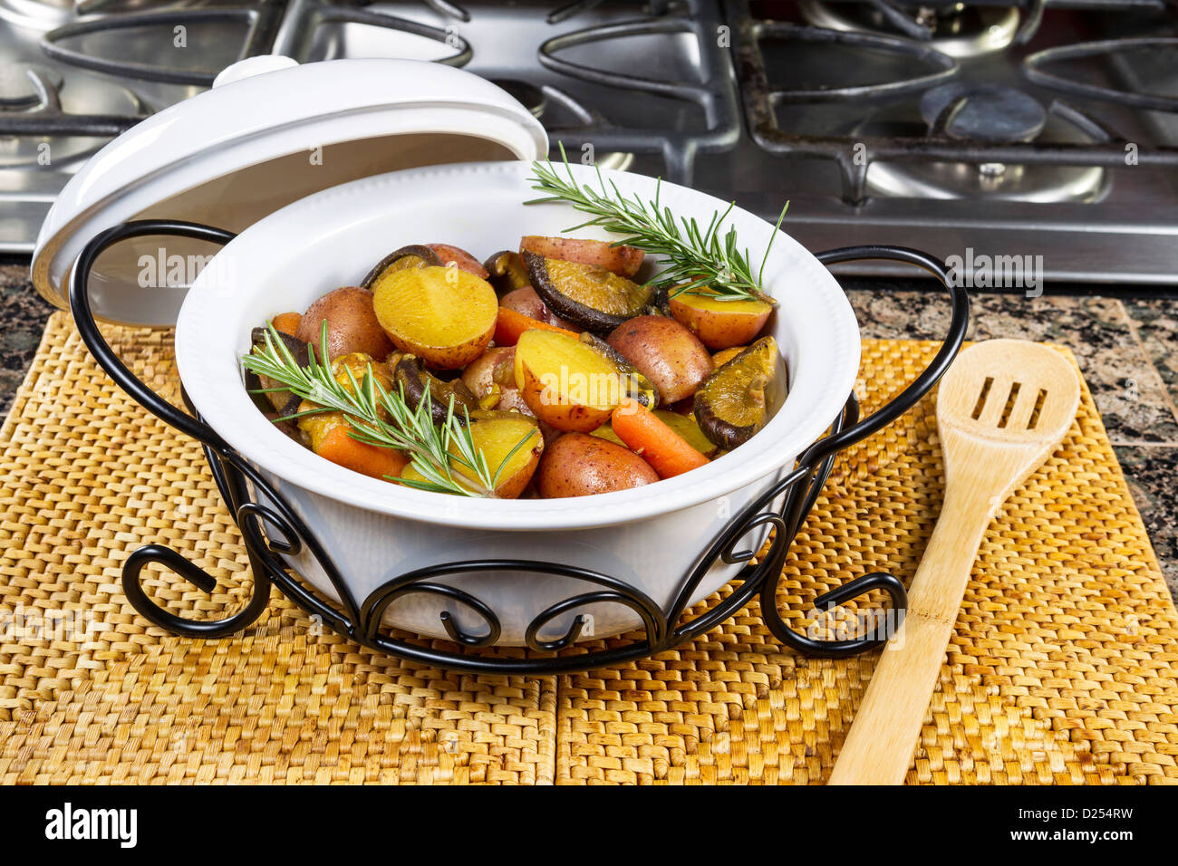 fresh curry chicken and vegetables in white dinner pot on kitchen counter top next to gas stove Stock Photo