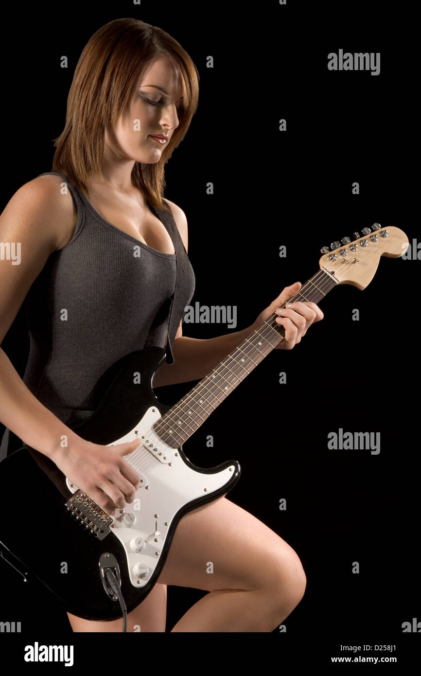 young Girl playing electric guitar in dark Stock Photo