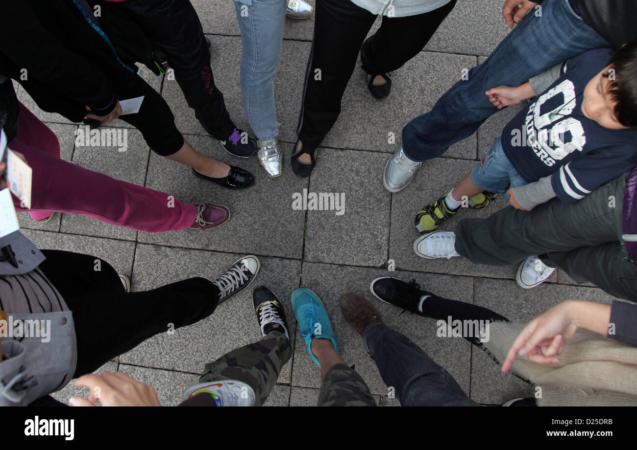 It's a photo view from the top of many people putting their foot side by side in circle to show their shoes. It's creative. Stock Photo