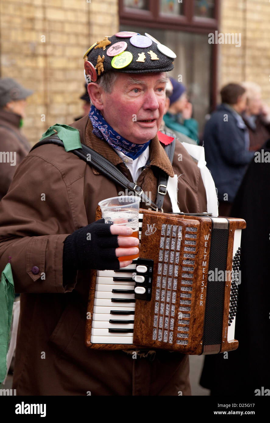 A musician man playing a melodeon accordion and drinking beer, Whittlesey straw bear festival, UK Stock Photo