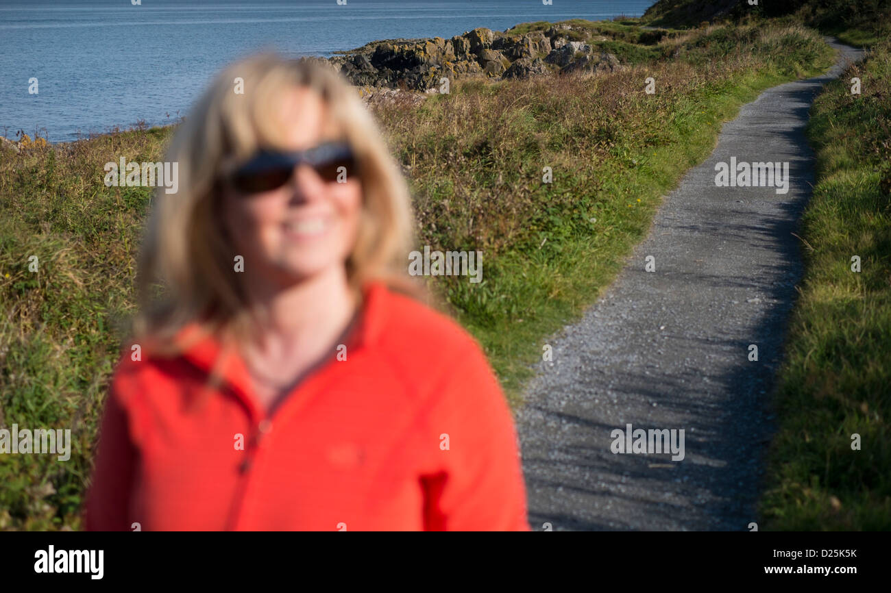 Woman walking on North Down coastal path along age of Belfast Lough Stock Photo