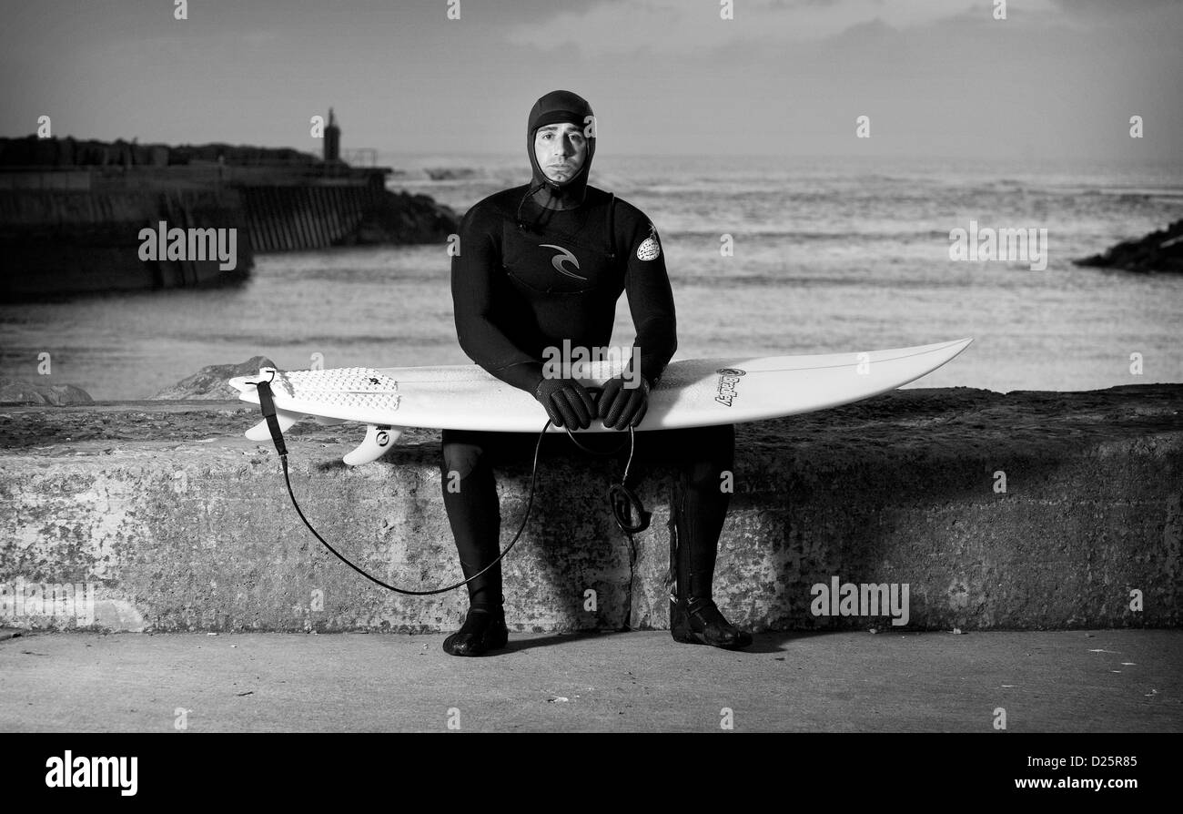 Surfer Fraser Camfield sits prior to going for an early morning surf in North Yorkshire, England. Stock Photo