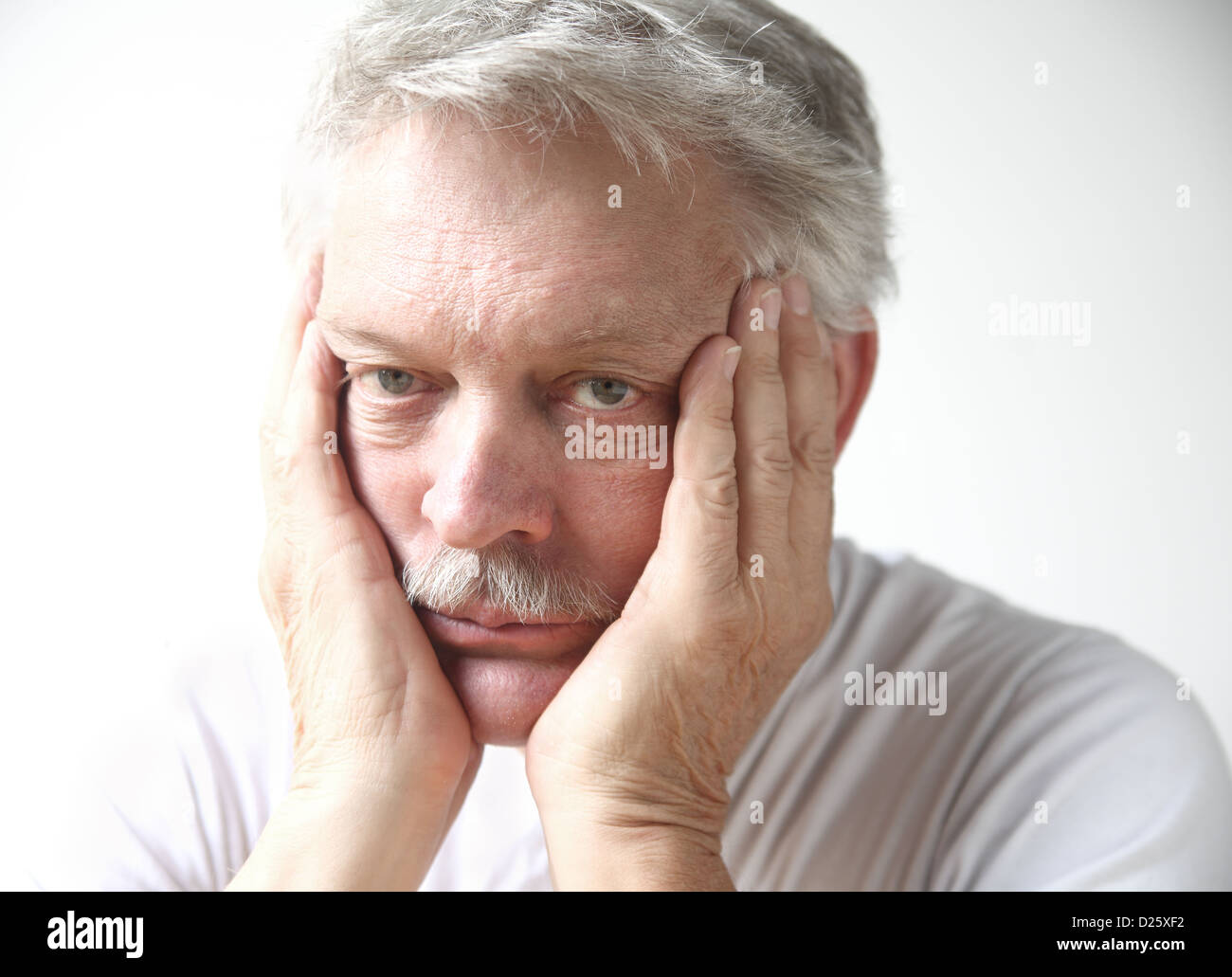 senior man rests his face in his hands and looks disappointed or bored ...