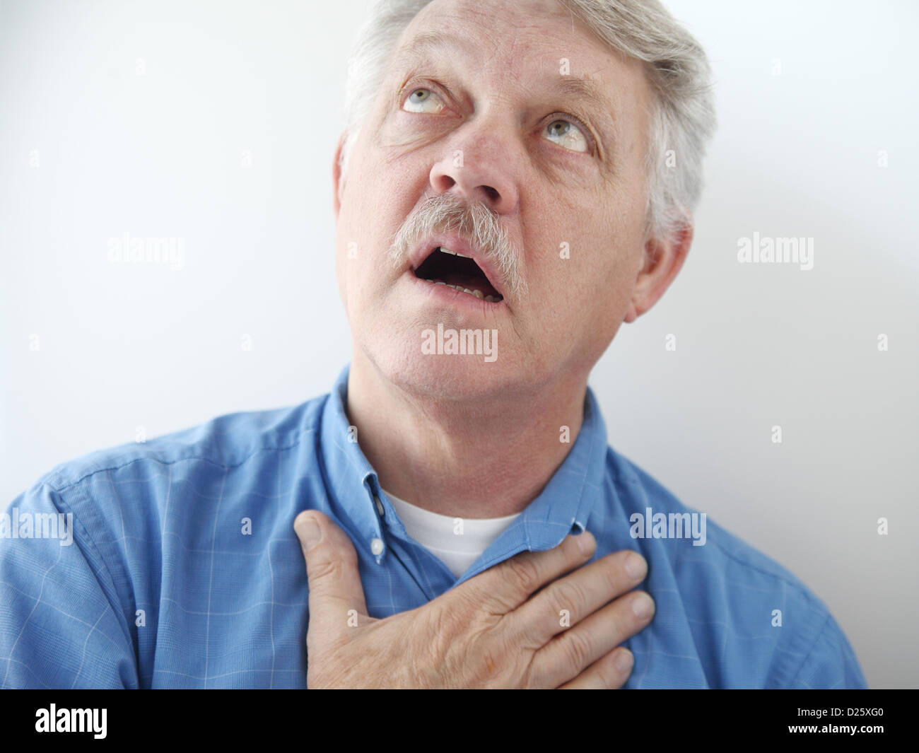 older man gazes skyward with a hand on his chest Stock Photo